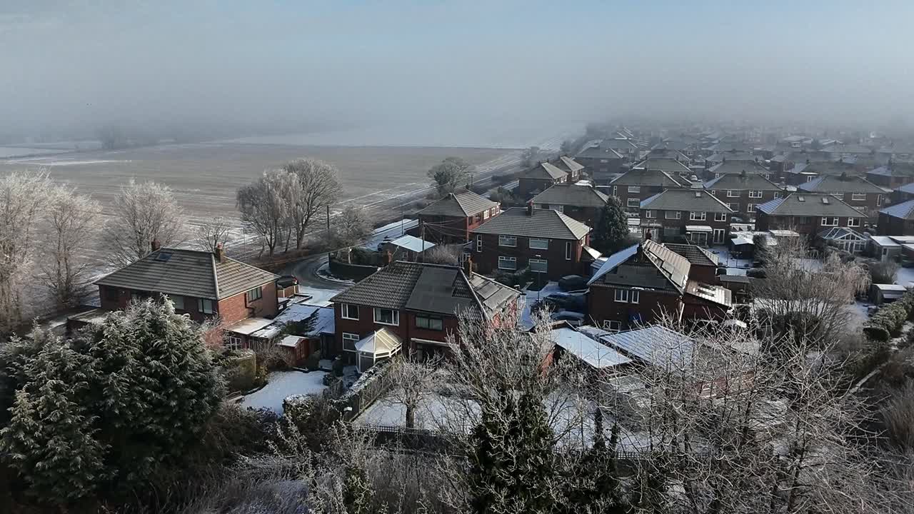 Frosty mist covering British small town suburb neighbourhood aerial view circling rooftops