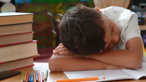 front view of asian schoolboy sleeping on desk in classroom at school 4k