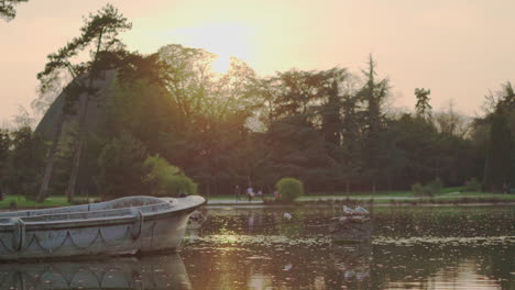 A-static-shot-of-an-abandoned-boat-in-the-middle-of-the-lake-of-the-Vincennes-Woods-Parc-at-sunset-in-Paris,-France