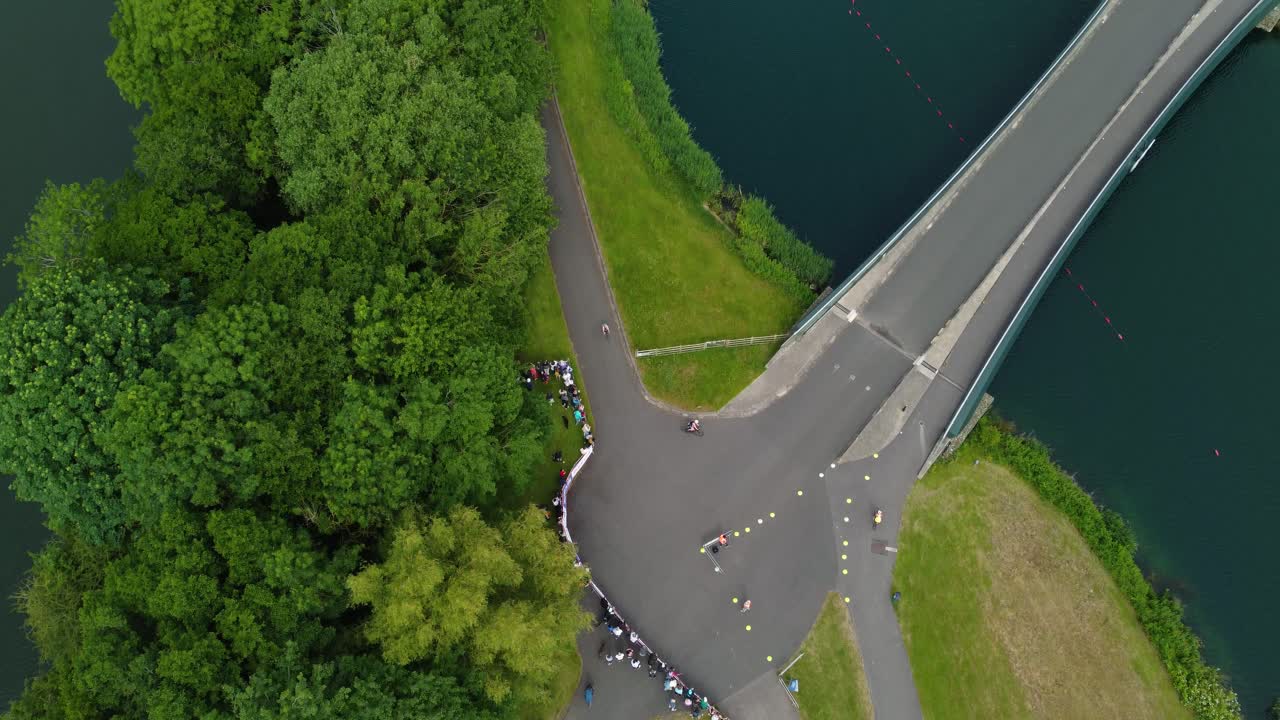 도르니 호수 (dorney lake) 에서 트라이애슬론 (triathlon) 의 아리엘   (ariel top shot) 은 자전거를 타고 트라이애틀론 선수들이 트랙에서 경쟁하며 물 다리를 건너고 있습니다.