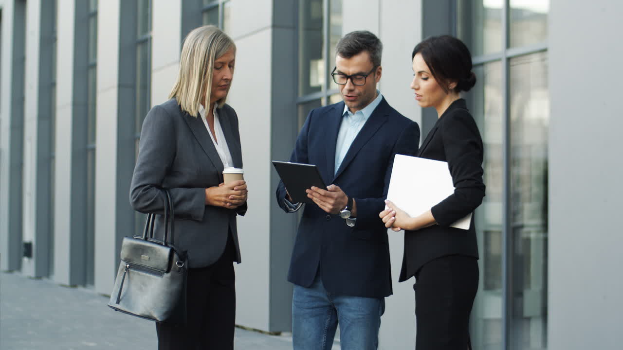 hombre de negocios con gafas y con tableta en las manos contando y describiendo algún proyecto de negocios a dos mujeres de negocios