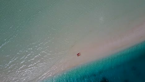 Pareja-Tendida-Boca-Abajo-En-La-Hermosa-Playa-De-Arena-Blanca-En-Maldivas-Con-Las-Olas-Frías-Corriendo---Toma-Aérea