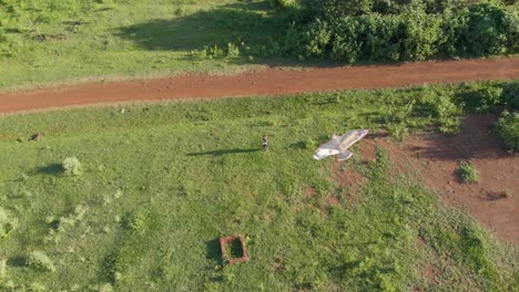 aerial shot looking down on a young boy flying a kite in the evening sun