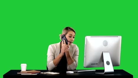 beautiful happy smiling young office woman working on computer at office desk attractive cheerful model in formal wear using smartphone and computer, making call during workday on a green screen, chroma key