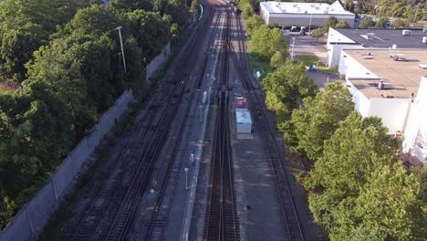 flying low over empty train tracks near a shopping center, a residential area and a highway