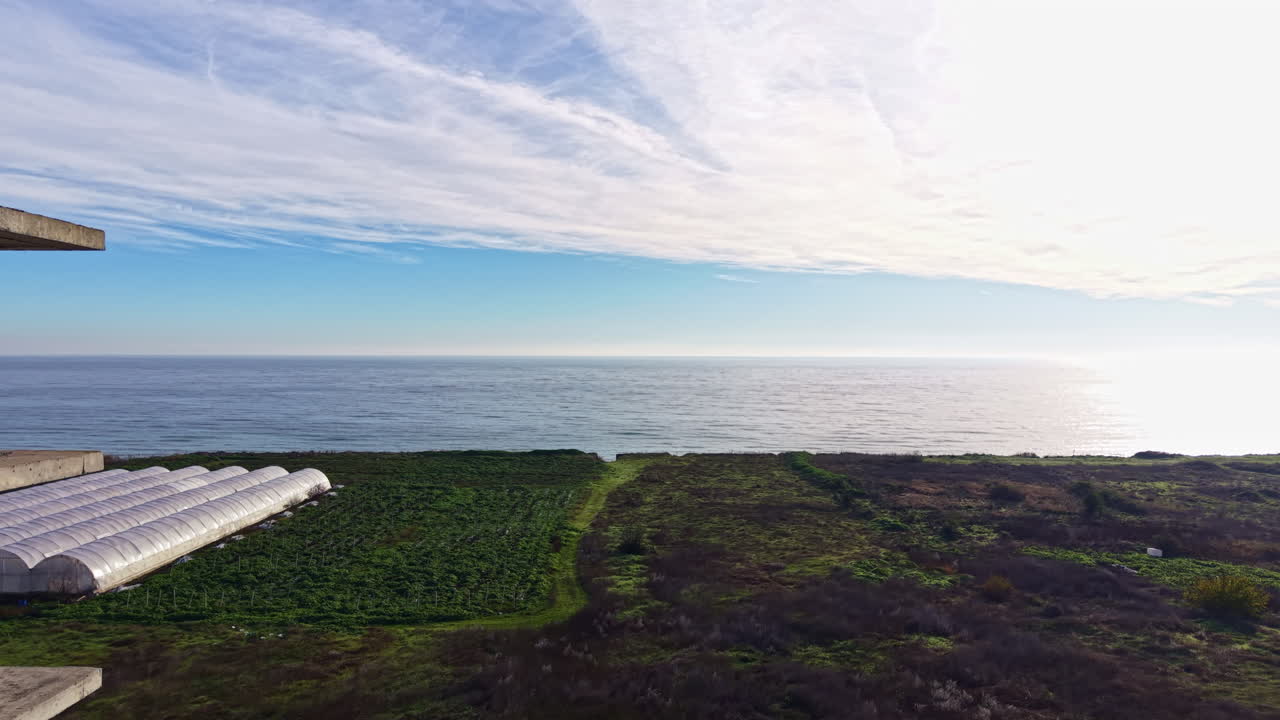 Vista costeira dramática através de um edifício abandonado ao pôr do sol, capturando ondas serenas e luz dourada