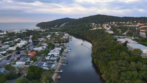 Barco-Navegando-En-Aguas-Tranquilas-Del-Río-Noosa-Con-Paisaje-Urbano-De-Noosa-Heads,-Queensland,-Australia