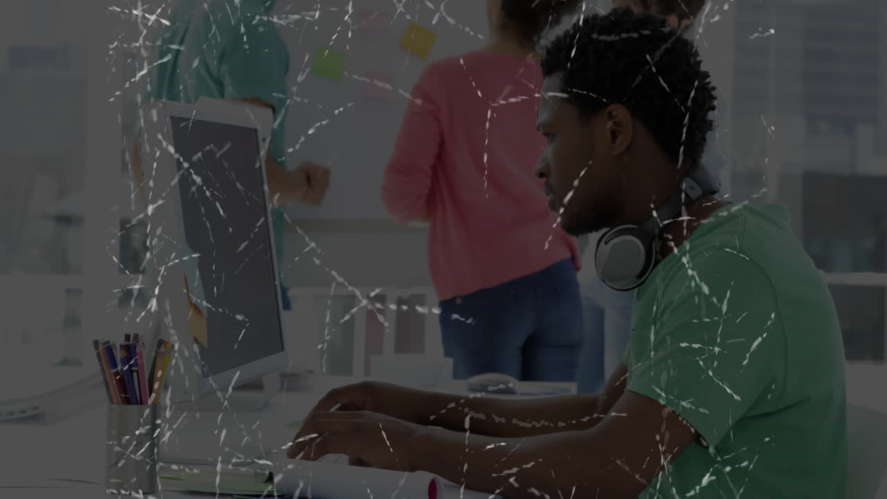 In office, man with headphones working on computer with animation software