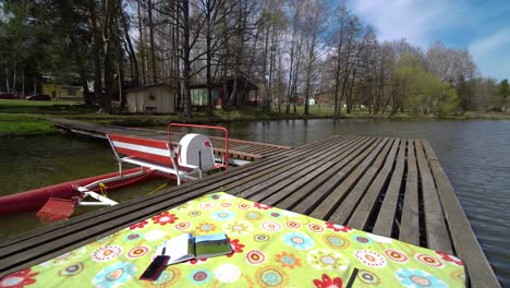 pedal boat parked at a wooden pier on a pond with blanket and a book on top