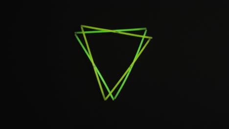 animation of green neon glow sticks forming triangles over black background with copy space