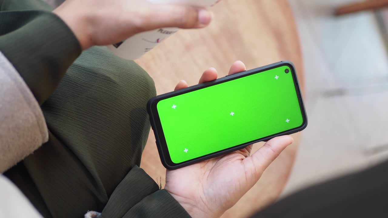 persona sosteniendo un teléfono con una pantalla verde