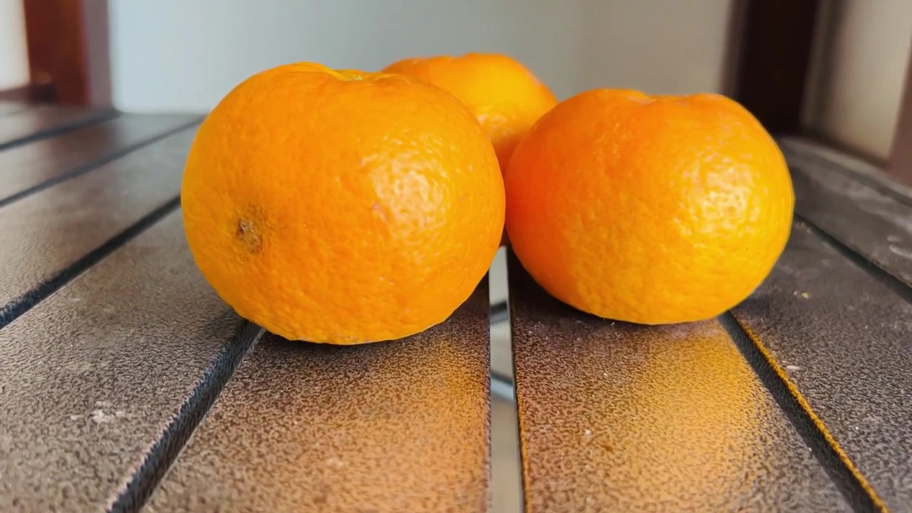 Drei frische Orangen auf einer strukturierten Tischoberfläche