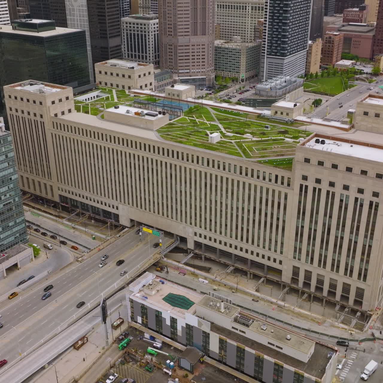 Wide multi-storied building in Chicago with beautiful green zone on the roof. Road going through the structure. Parking lot at foreground
