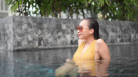 isolated beautiful woman relaxing in outdoor hotel swimming pool slomo