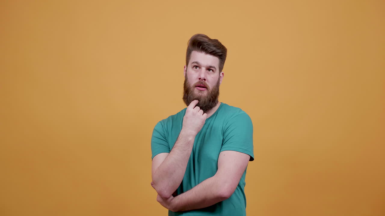 Thoughtful man with beard on orange background