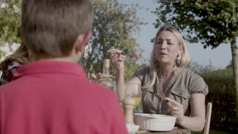 happy man, woman and teenage daughter having dinner outdoors