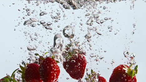 red strawberry falling water in super slow motion close up. fresh berry sinking.