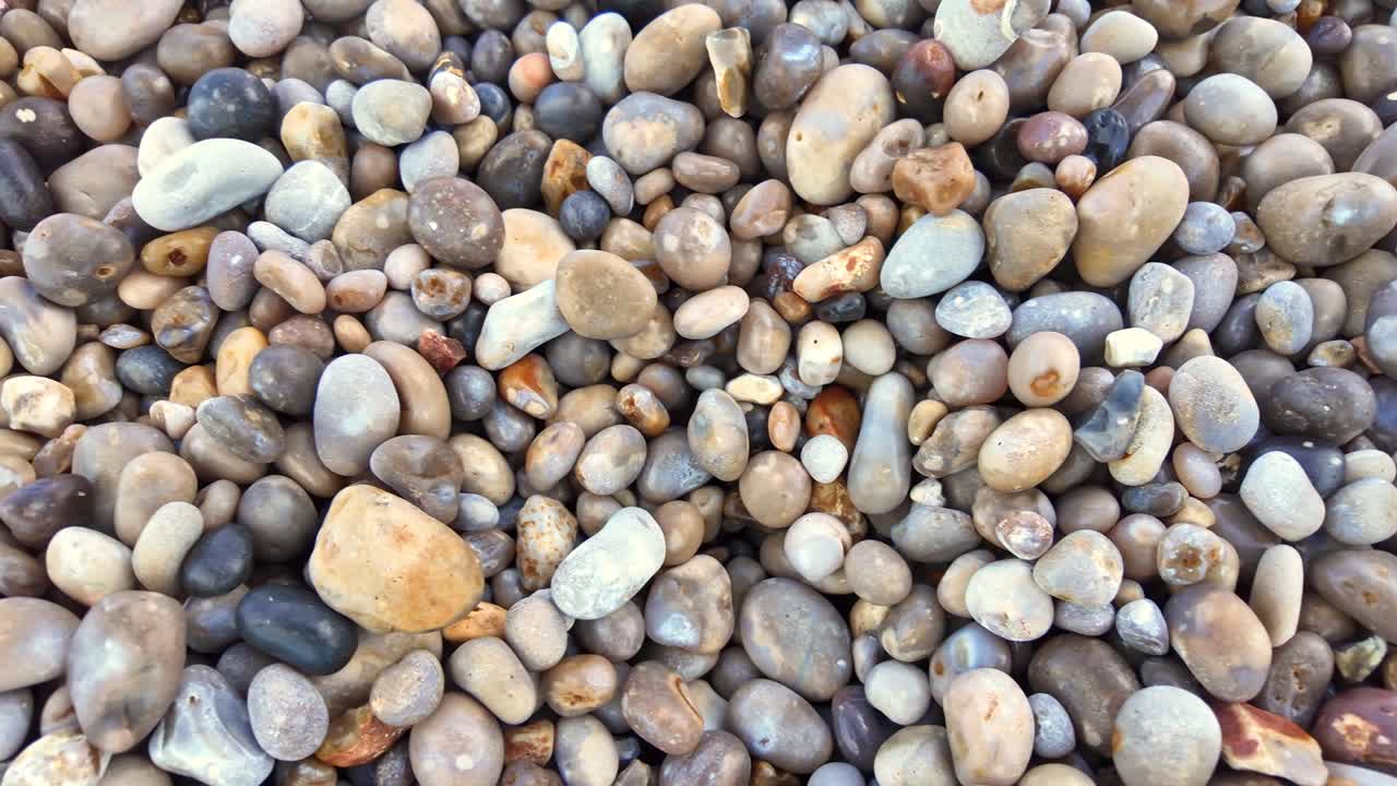 Makroaufnahme von nassen, glatten, abgerundeten Kieselsteinen und Steinen am berühmten Strand von Étretat in der Normandie, Frankreich