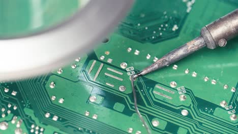 technician soldering circuit pin on electronic board, computer repair