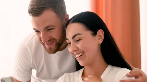 primer plano de una pareja sonriente que tiene una videollamada en un teléfono inteligente en casa