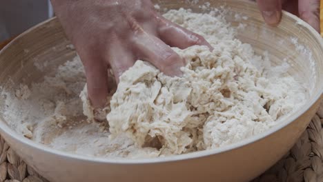 chef molds the pizza dough in a deep plate, on a wooden table