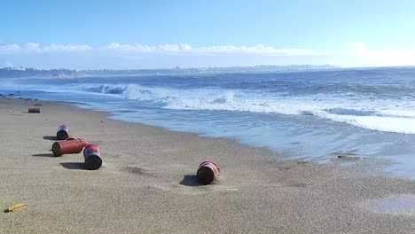 static shot of the plastic and metal debris washes up on the beach near a wavy ocean, water pollution plastic pollutions