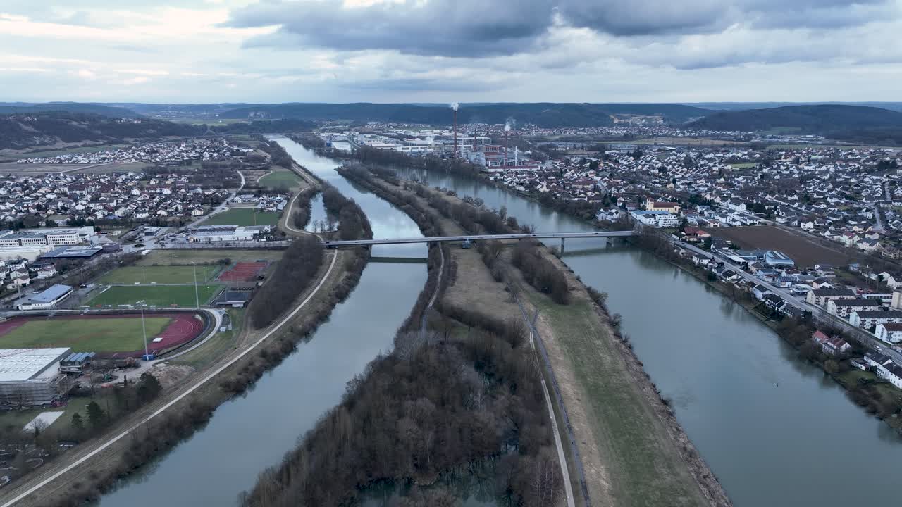 Aerial view of the confluence of the Main-Danube Canal and the Danube River near Kelheim, Germany, featuring a split waterway and industrial area
