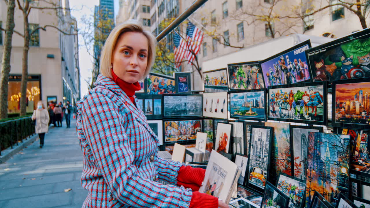 New York, USA, 5 October 2025: Woman looking at street art stand in New York City. Profile of woman in plaid suit examining posters at an outdoor art market on a Manhattan sidewalk
