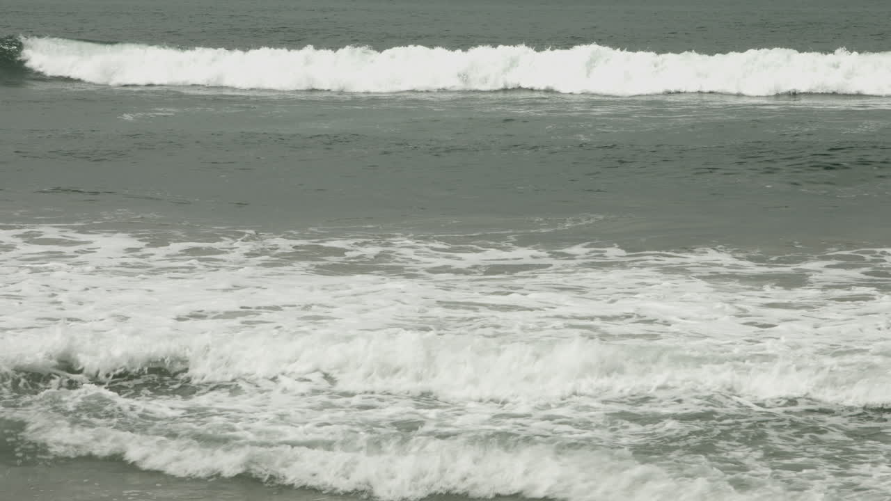 A middle-aged lone surfer paddles out in the ocean beneath an overcast sky, captured in a UHD medium shot, surrounded by calm water, lost in thought as the quiet morning swells around him