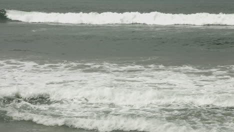 a middle-aged lone surfer paddles out in the ocean beneath an overcast sky, captured in a uhd medium shot, surrounded by calm water, lost in thought as the quiet morning swells around him