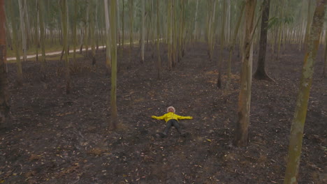 drone shot reveals a male in yellow jacket lying on forest ground and relaxing in terai region of eastern nepal