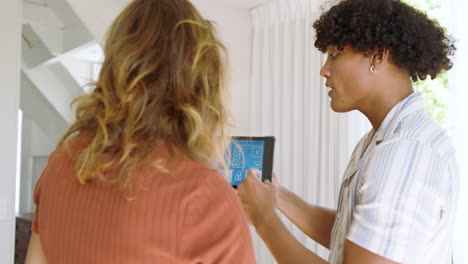 diverse couple using tablet to control smart home features, discussing settings together
