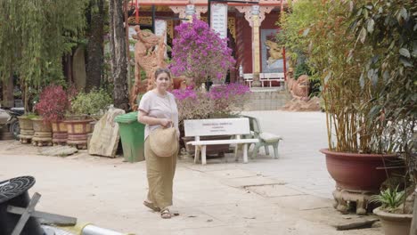 a woman in her 30s is exploring a temple under the golden buddha statue in da lat, vietnam