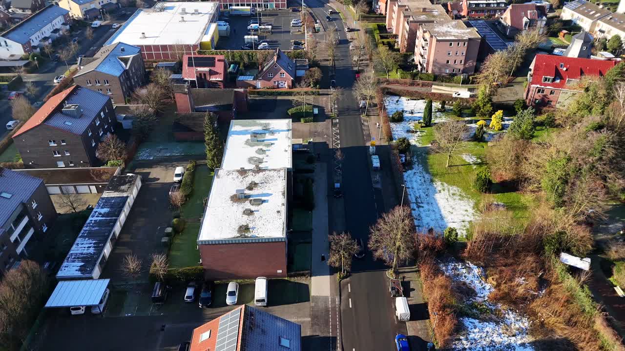 Cold and frosty winter day with sunlight in german neighborhood. Dripping cars in street. Solar panels on houses. Aerial top down flyover.