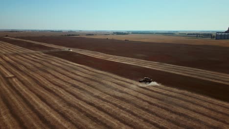 rising drone shot pair of combines farming a single crop of land in the midwest