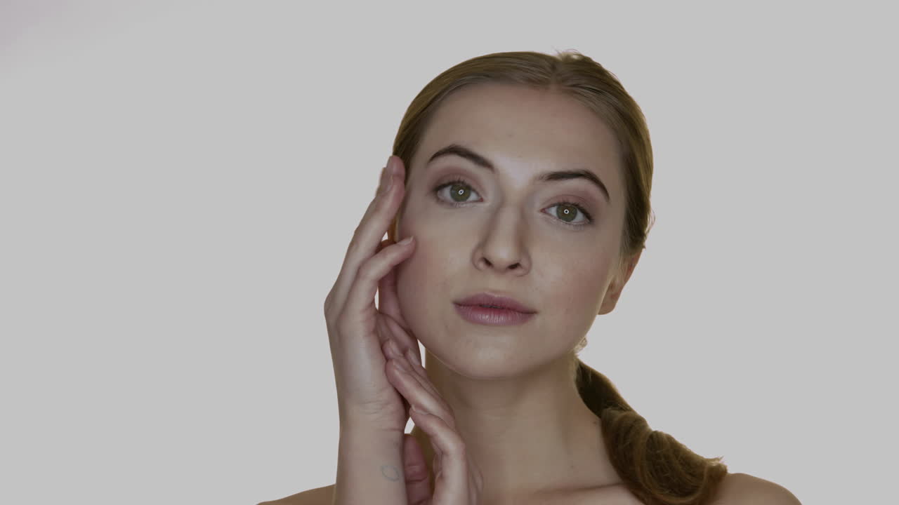 una mujer sonriente de fondo blanco toca su cara con la mano
