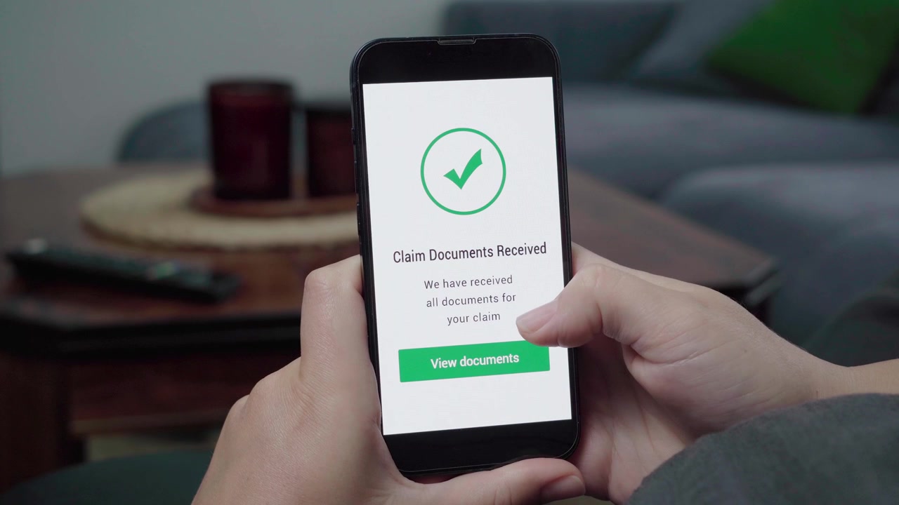 Una persona controlla un messaggio di successo "Documenti di reclamo ricevuti" con una spunta verde e un pulsante "Visualizza documenti" su un telefono.