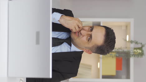 vertical video of home office worker man biting his nails looking at camera.