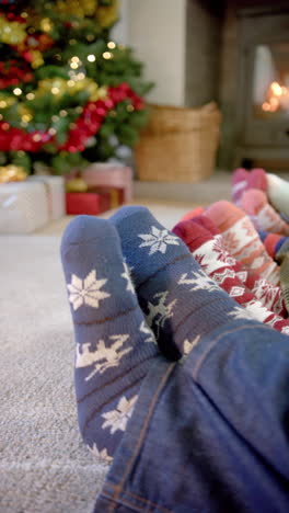 Vertical video of feet of family in warm socks fireplace at christmas, copy space, slow motion