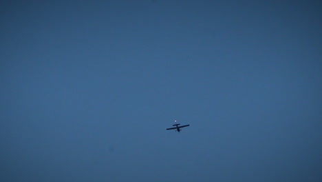 Close-up-of-a-small-plane-flying-over-a-city-at-night