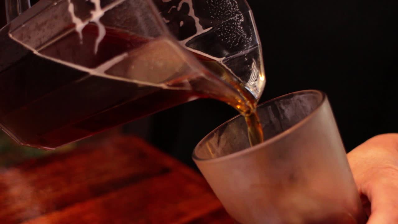 A pint of beer being poured from a jug.