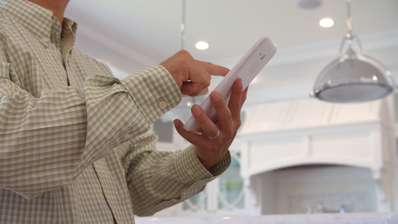 Man Using Digital Tablet To Control Lighting At Home