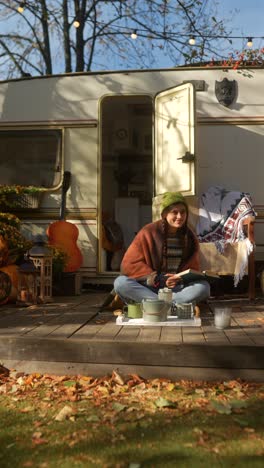 woman reading a book on a camper patio in autumn