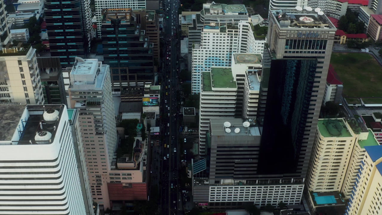 Vista de drone para a frente com ruas movimentadas entre arranha-céus de Bangkok.