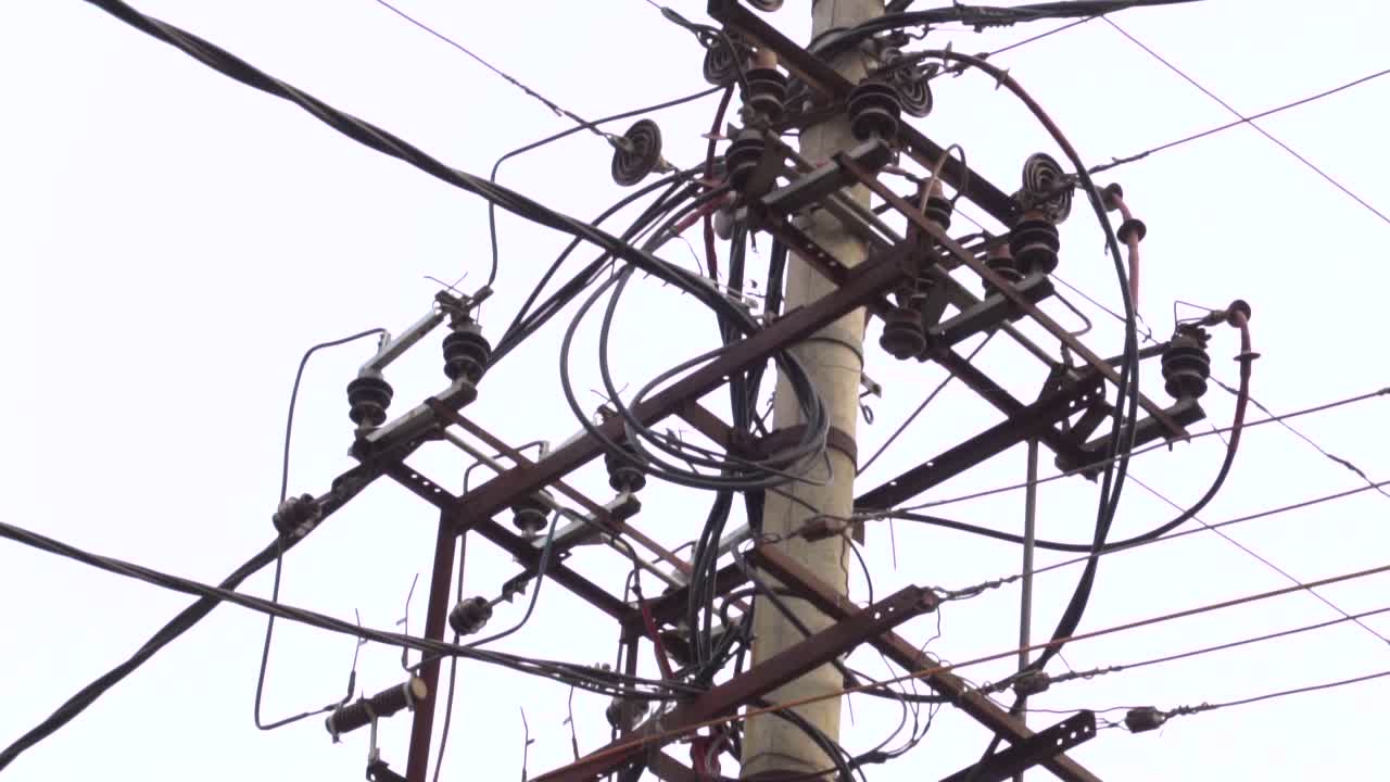 cámara lenta de un transformador con cables enredados aislados contra un cielo nublado, 60 fps
