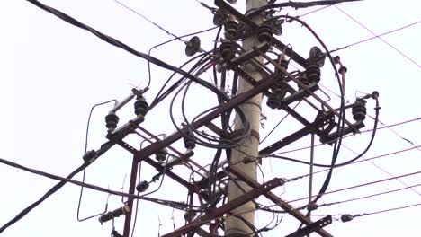 slow motion pan of a transformer with tangled wires isolated against an overcast sky, 60 fps