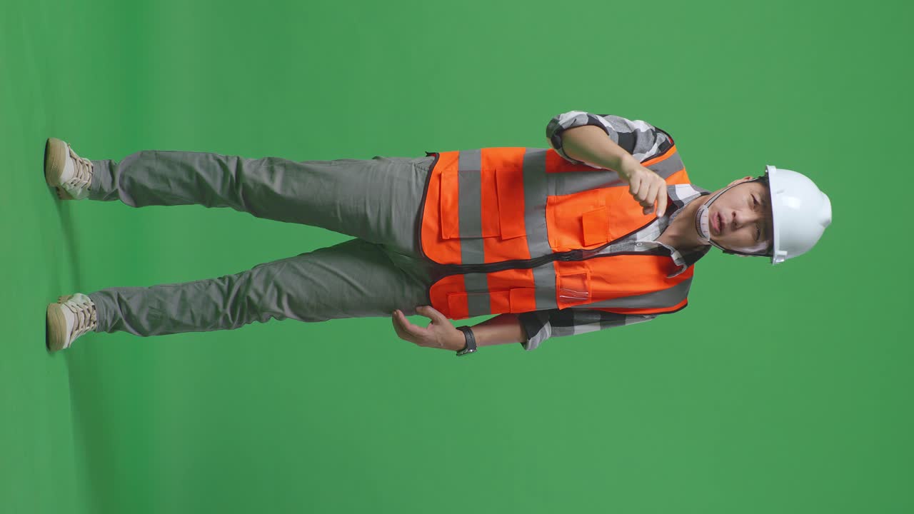 Full Body Of Angry Asian Male Engineer With Safety Helmet Shouting At Someone While Standing In The Green Screen Background Studio
