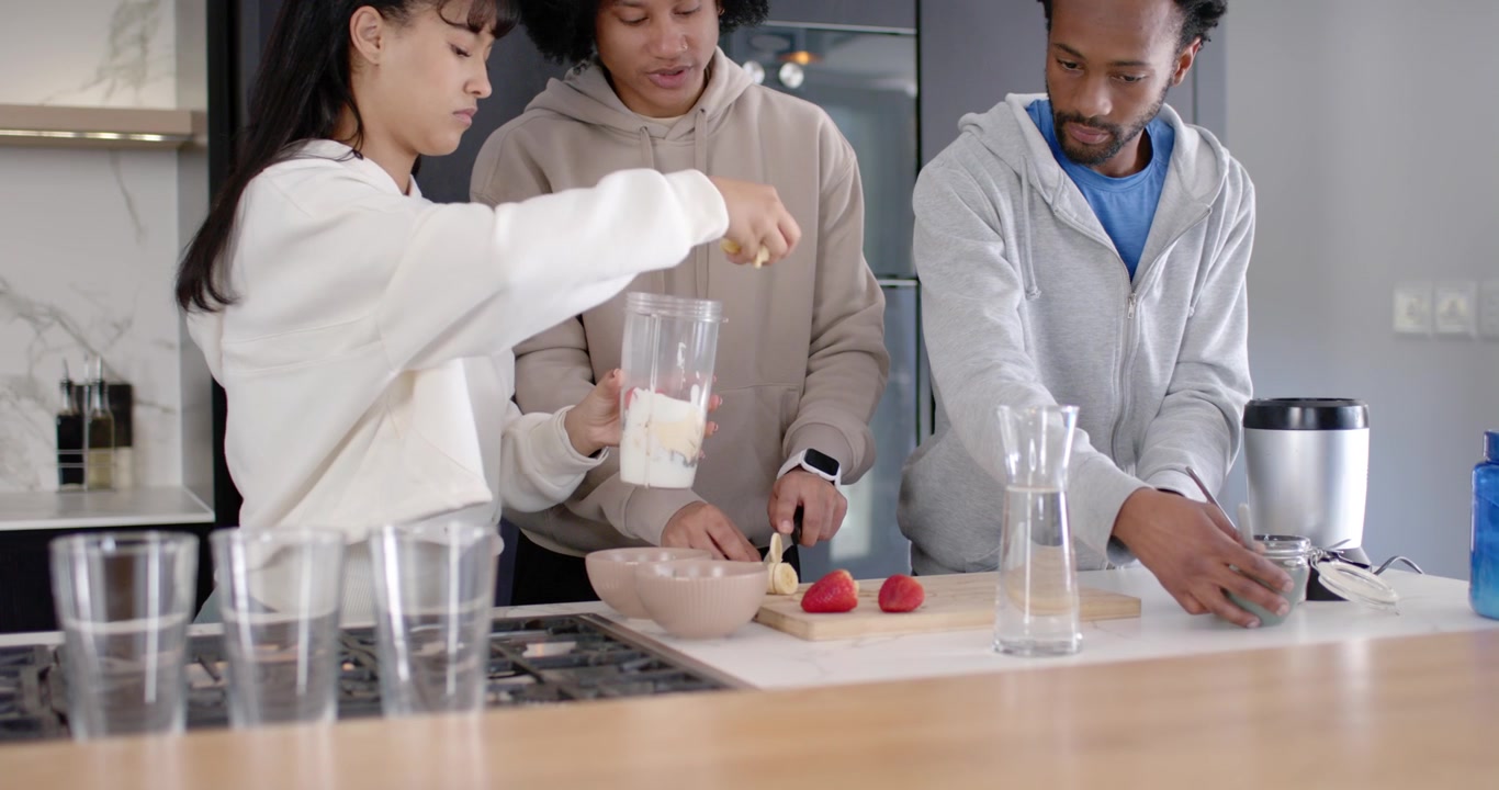 Amici Diversi che Preparano un Frullato sull'Isola della Cucina, con Ring Light Accesa, Aggiungendo Latte al Frullatore