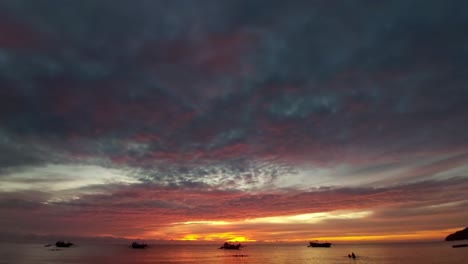 una escena de ensueño de barcos de pesca amarrados en el vasto horizonte con la silueta de la colorida puesta de sol de verano, que representa la vida cotidiana en la isla paraíso de siocon, filipinas.