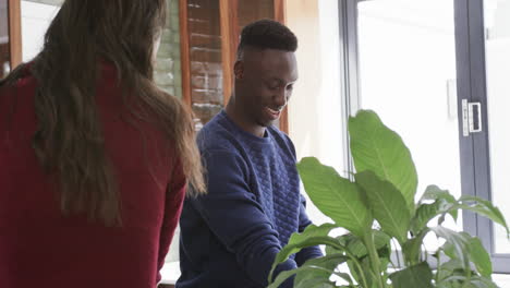 Happy-diverse-couple-standing,-talking-and-smiling-in-kitchen,slow-motion